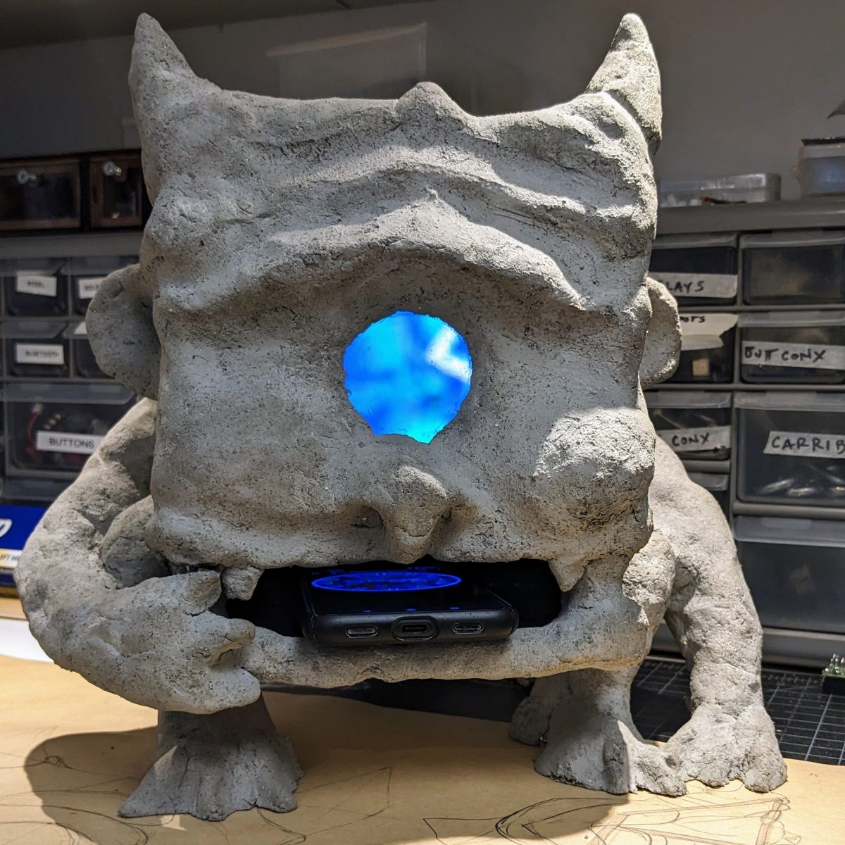 A gargoyle sculpture with a phone on its mouth,